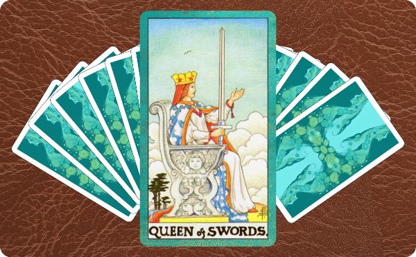 Image of Rider Waite Queen of Swords tarot card on top of a deck of cards.