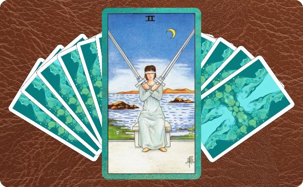 Rider Waite depiction of the Two of Swords tarot card sitting on top of a spread of other cards.