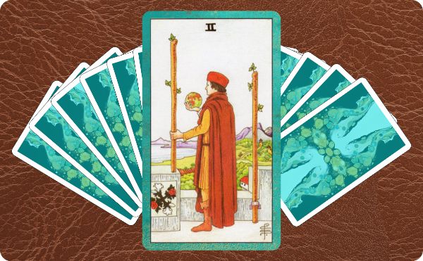 Rider Waite depiction of the Two of wands tarot card sitting on a spread of other tarot cards.