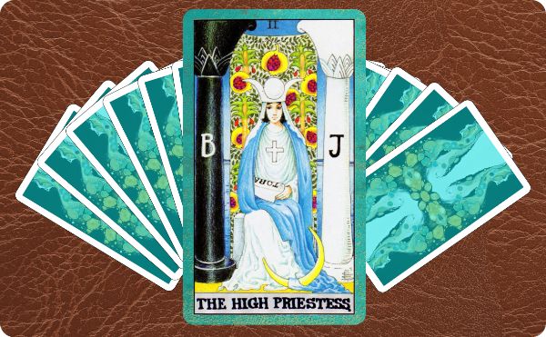 Rider Waite depiction of The High Priestess tarot card sitting on a spread of other cards