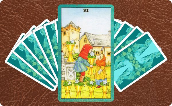 Rider Waite depction of the six of cups tarot card sitting on top of a sperad of other cards.