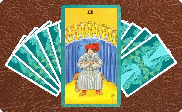 Rider Waite depiction of the Nine of Cups tarot card sitting on top of a spread of other cards.