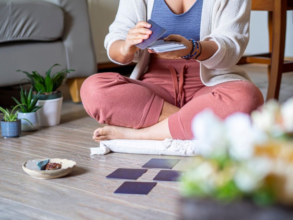 Woman sitting on floor laying out a tarot card spread